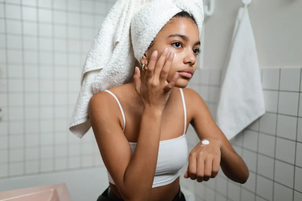 Girl applying cream on her face. 