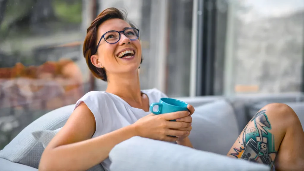 Lady is smiling while having a cup of tea. 